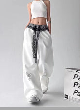 Person wearing white pants with black floral patterns on a gray background